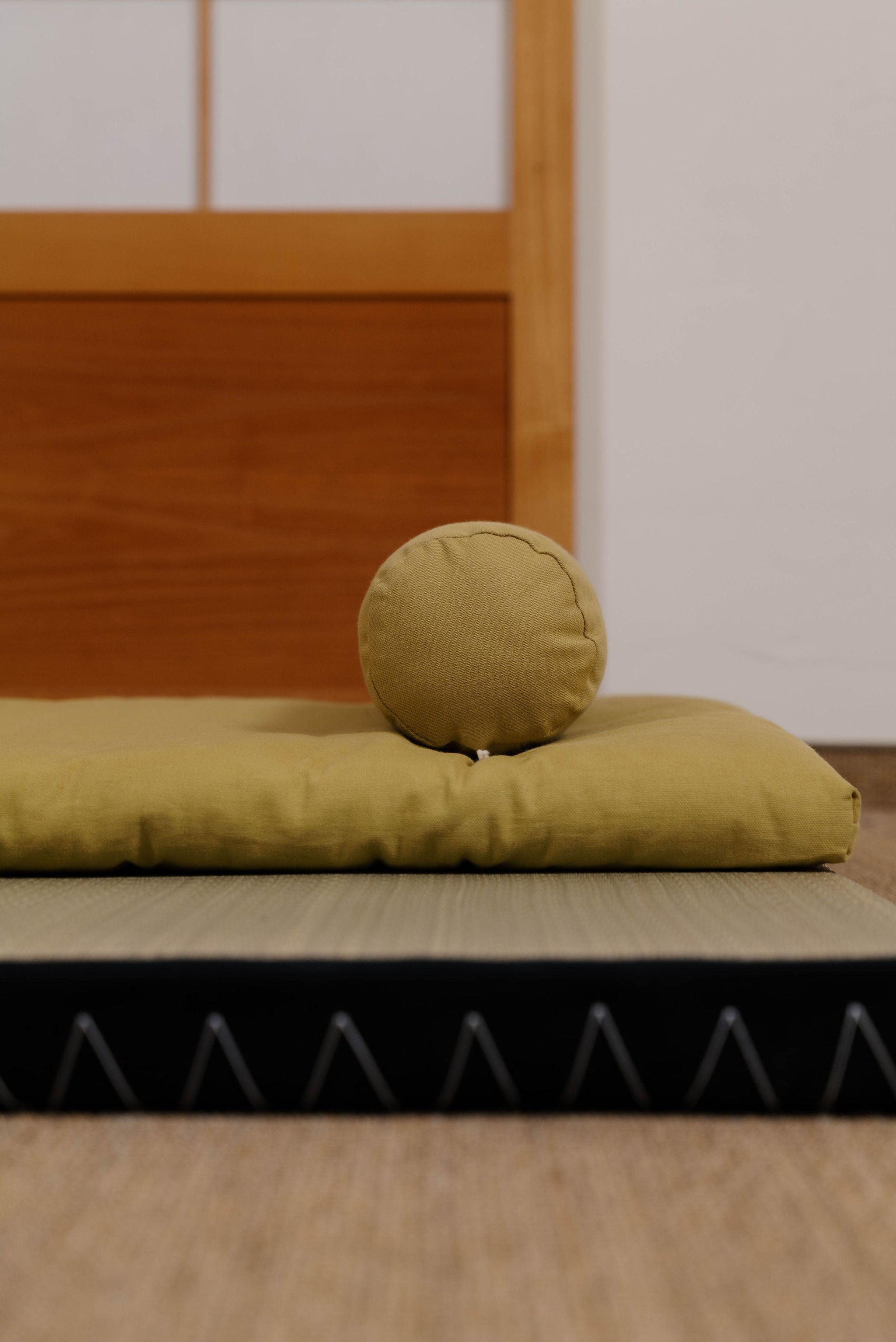 Gelber Futon liegt mit Nackenstütze auf dem Boden bei Futomania Detailaufnahme